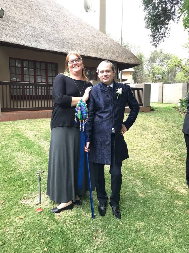 Lesley smiling with a couple at an outdoor wedding ceremony
