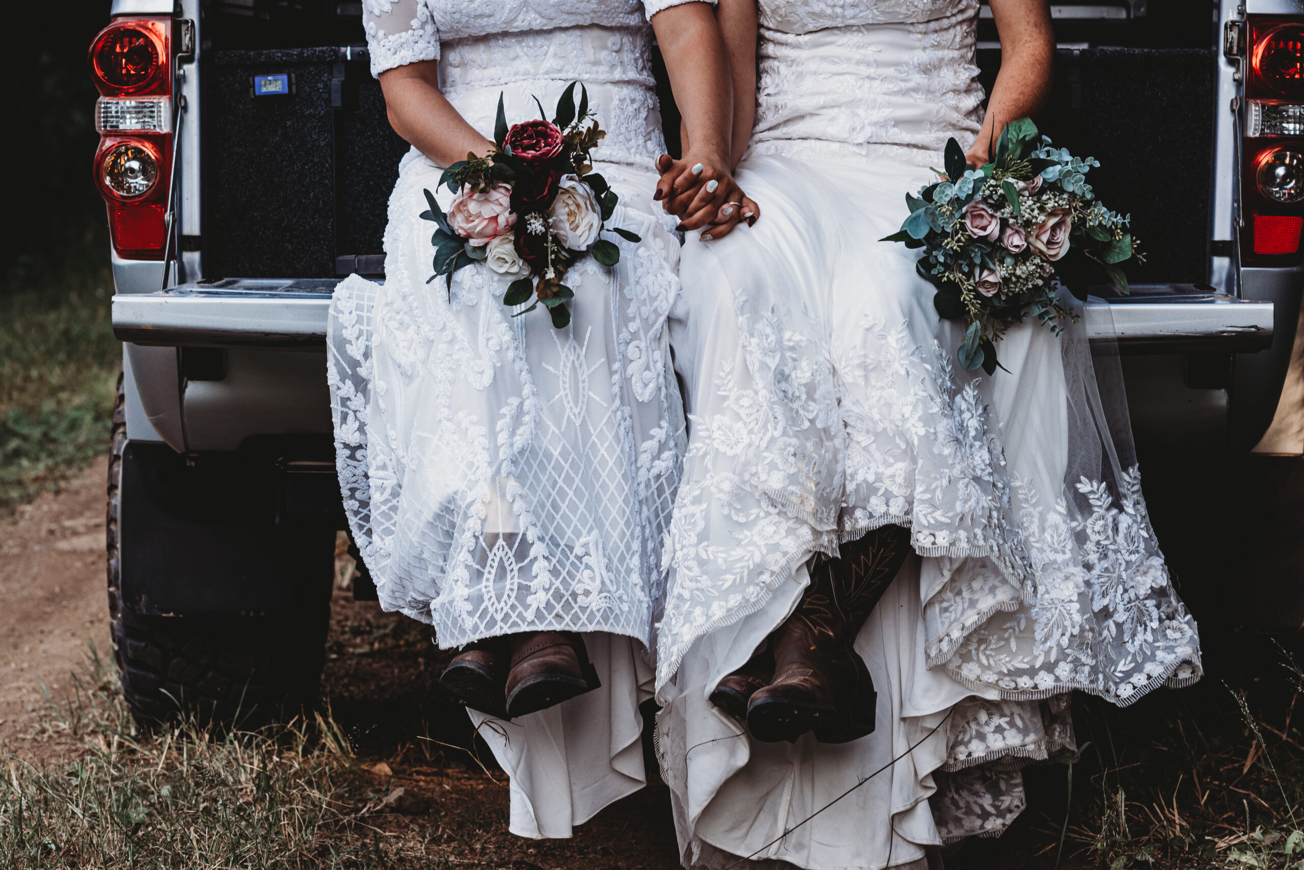 Two brides sitting in the back of a truck showing their shoes